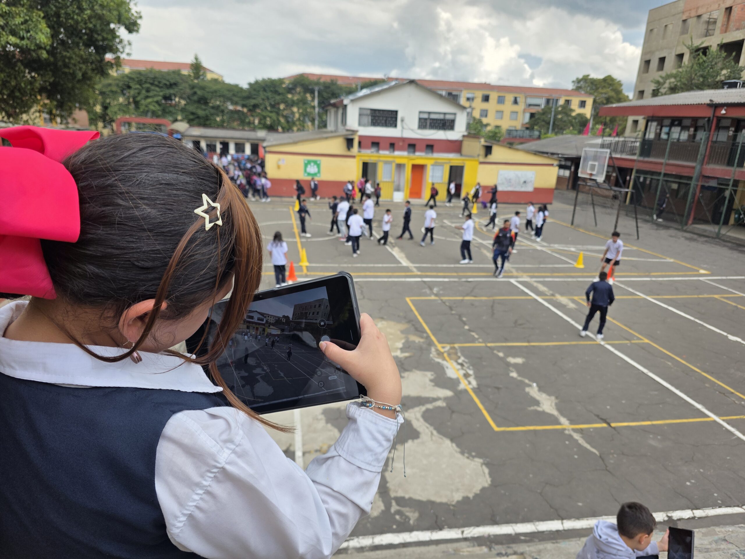 Estudiante fotografía el patio del colegio desde el segundo nivel durante el descanso