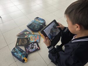 Estudiante fotografía con la tablet varias portadas de libros dispuestas en el suelo