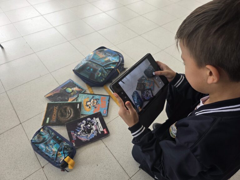 Estudiante fotografía con la tablet varias portadas de libros dispuestas en el suelo
