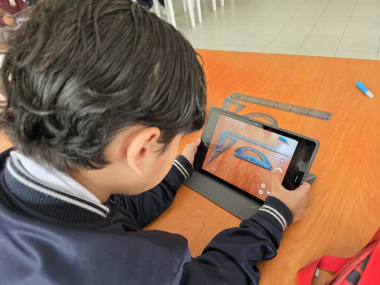 Estudiante fotografía con la tablet instrumentos de geometría sobre una mesa