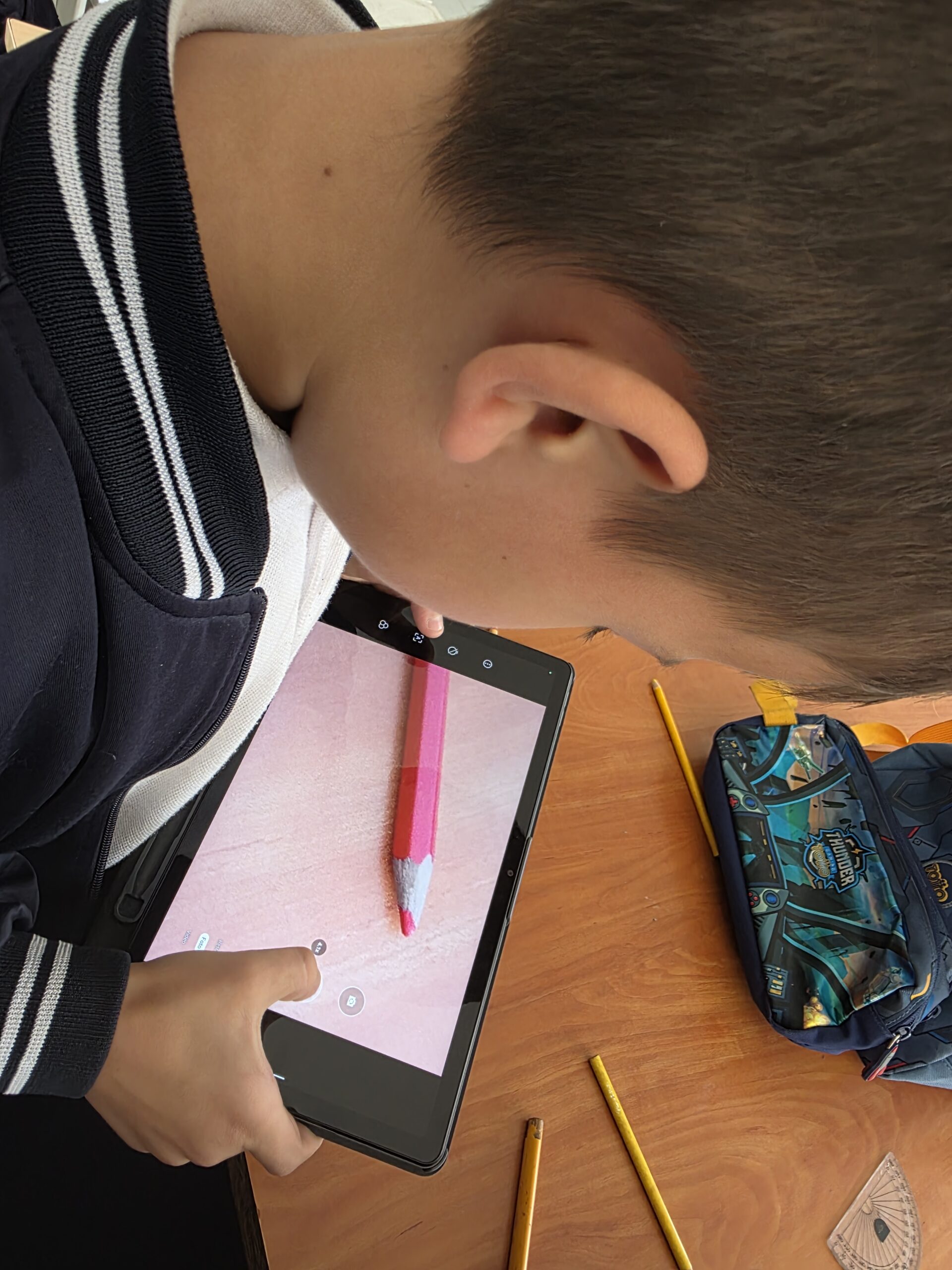 Estudiante hace una macrofotografía de la punta de un lápiz de color rosado con la tablet
