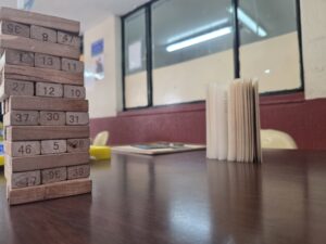 Juego de bloques de madera con números junto a libros sobre una mesa de la biblioteca escolar