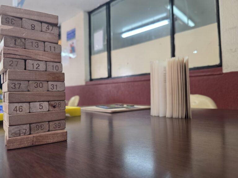 Juego de bloques de madera con números junto a libros sobre una mesa de la biblioteca escolar