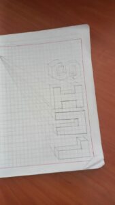 Letras dibujadas con volumen isométrico y líneas de fuga sobre papel cuadriculado
