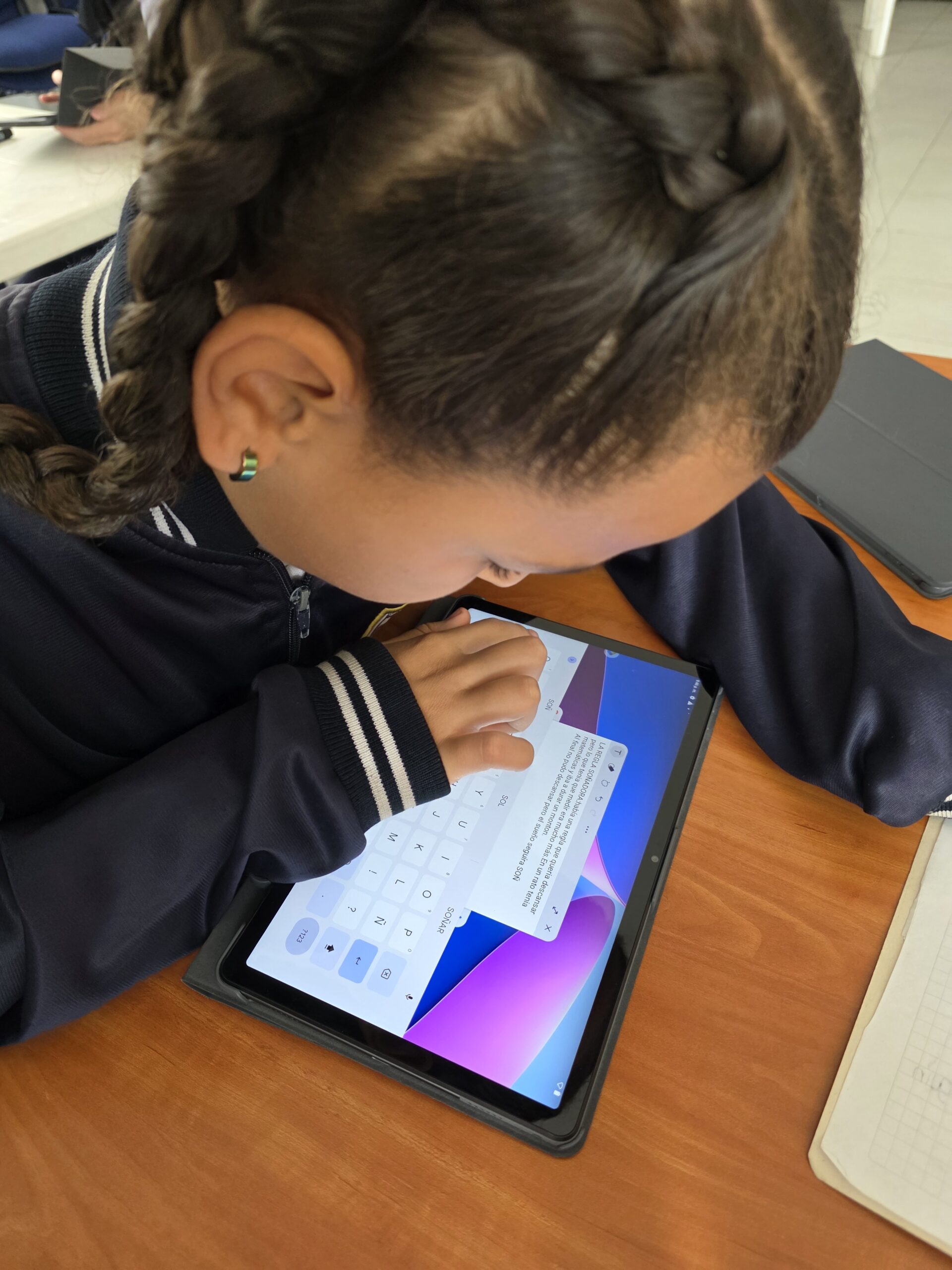 Estudiante escribe un cuento en la pantalla de una tablet usando el teclado