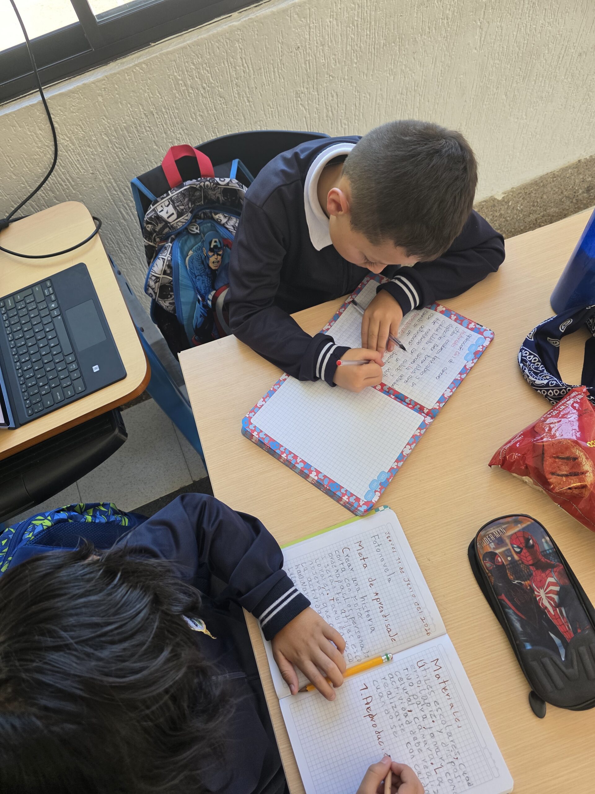Dos estudiantes escriben en sus cuadernos para planear una historia