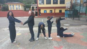 Grupo de estudiantes forma letras con brazos y cuerpo en la cancha del colegio