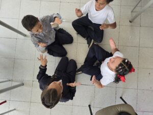 Vista desde lo alto del grupo de estudiantes sentado en círculo durante el juego de manos