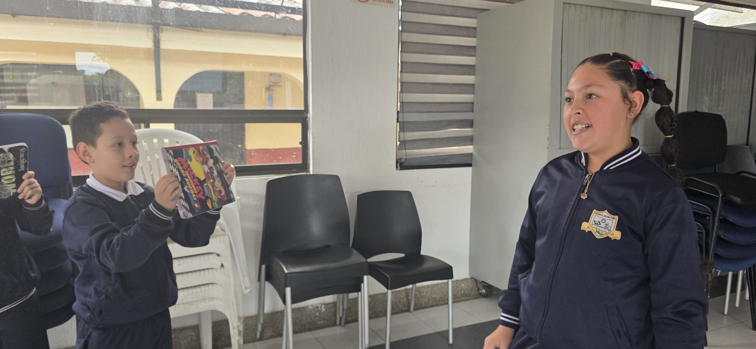 Un estudiante graba con una tablet mientras una compañera responde la entrevista en el salón