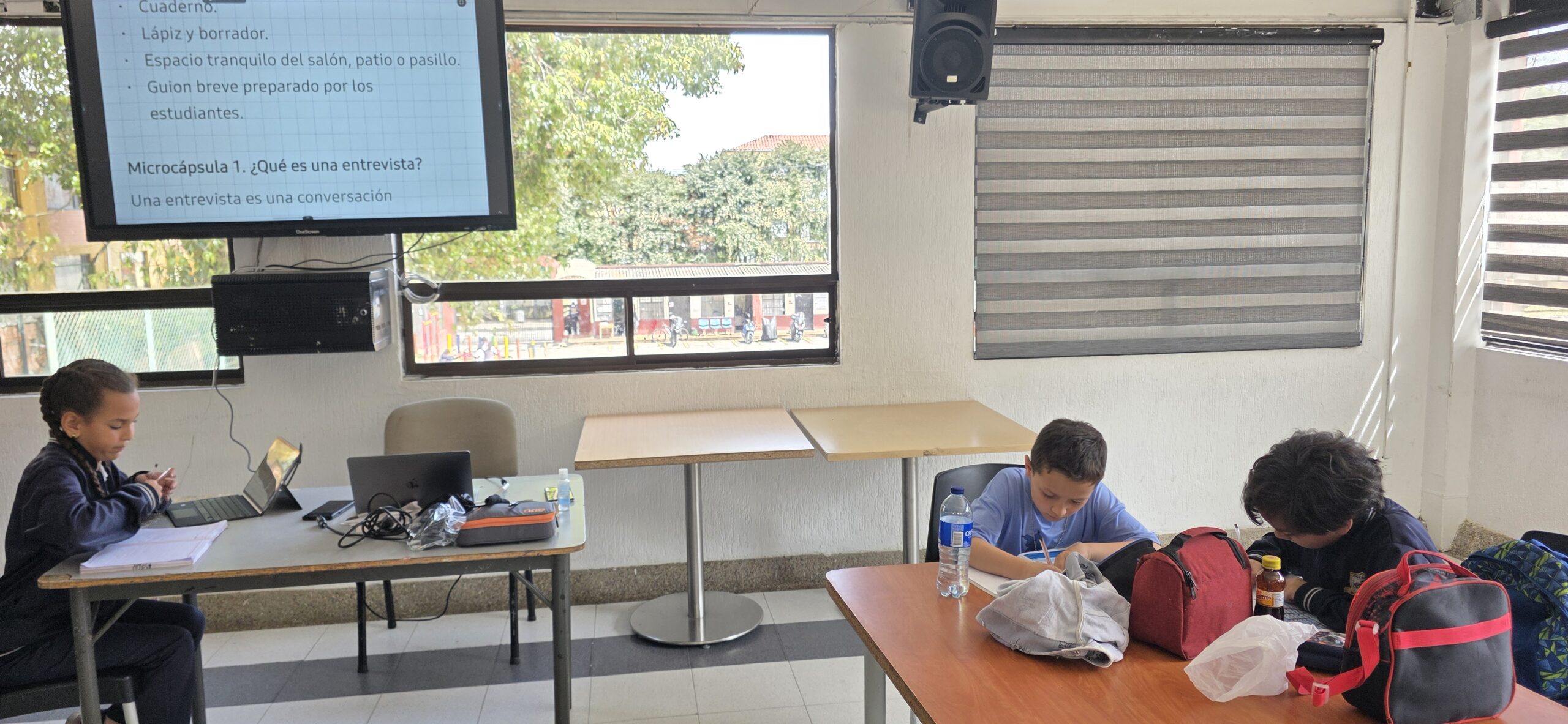 Diapositiva proyectada con los materiales de la sesión y la microcápsula «¿Qué es una entrevista?» mientras los estudiantes trabajan en sus cuadernos