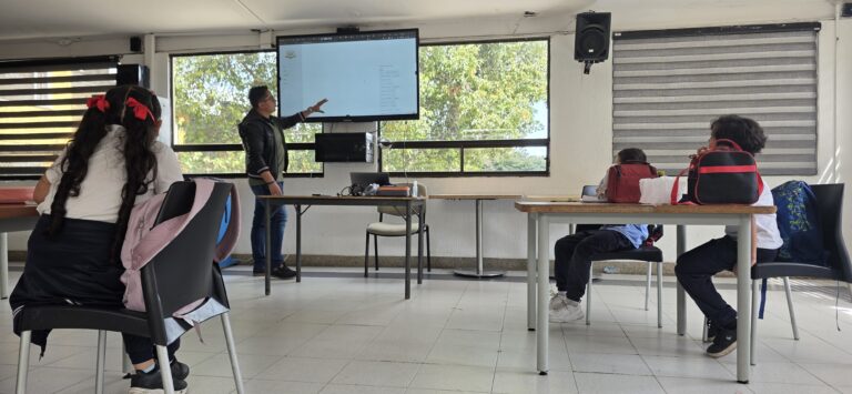 El docente presenta la agenda de la sesión ante el grupo en el salón del taller