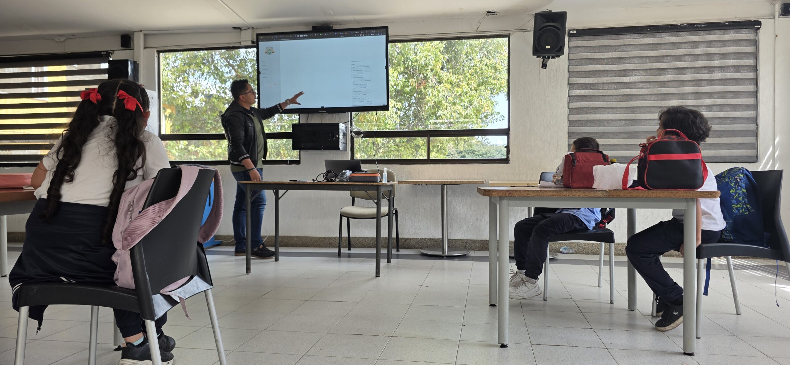 El docente presenta la agenda de la sesión ante el grupo en el salón del taller