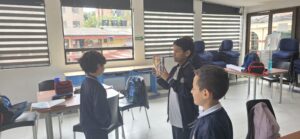 Estudiante graba con una tablet mientras sus compañeros observan la presentación frente a la cámara