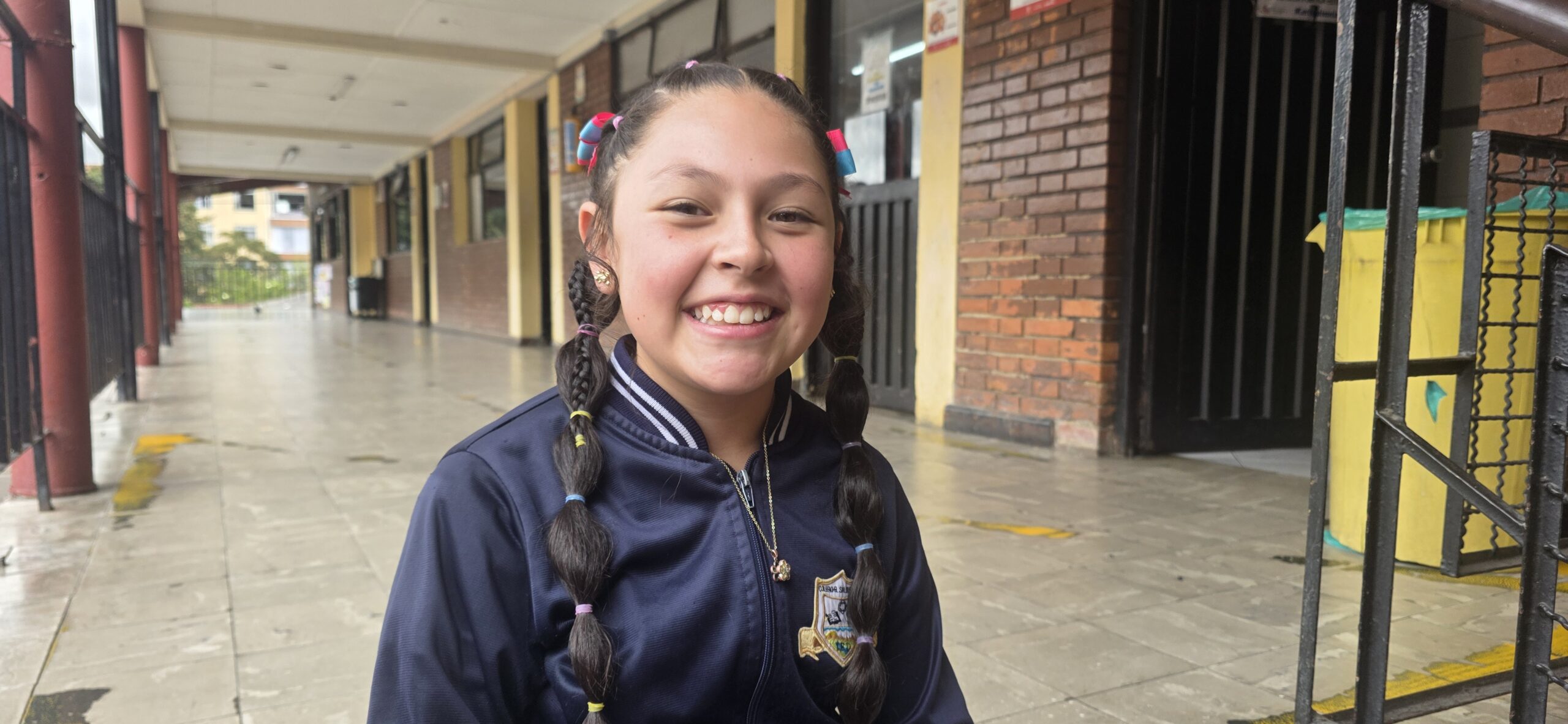 Retrato de una estudiante sonriendo en el corredor del colegio después de grabar su presentación