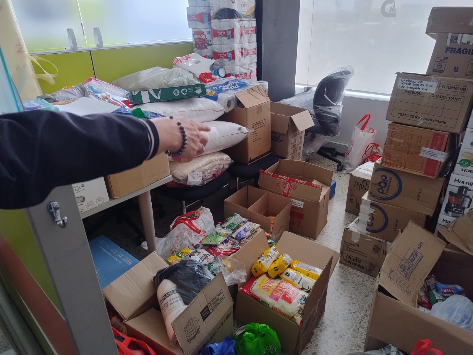 Cajas de donaciones apiladas en una oficina del colegio: alimentos, papel higiénico, cobijas y almohadas listos para salir al punto de acopio