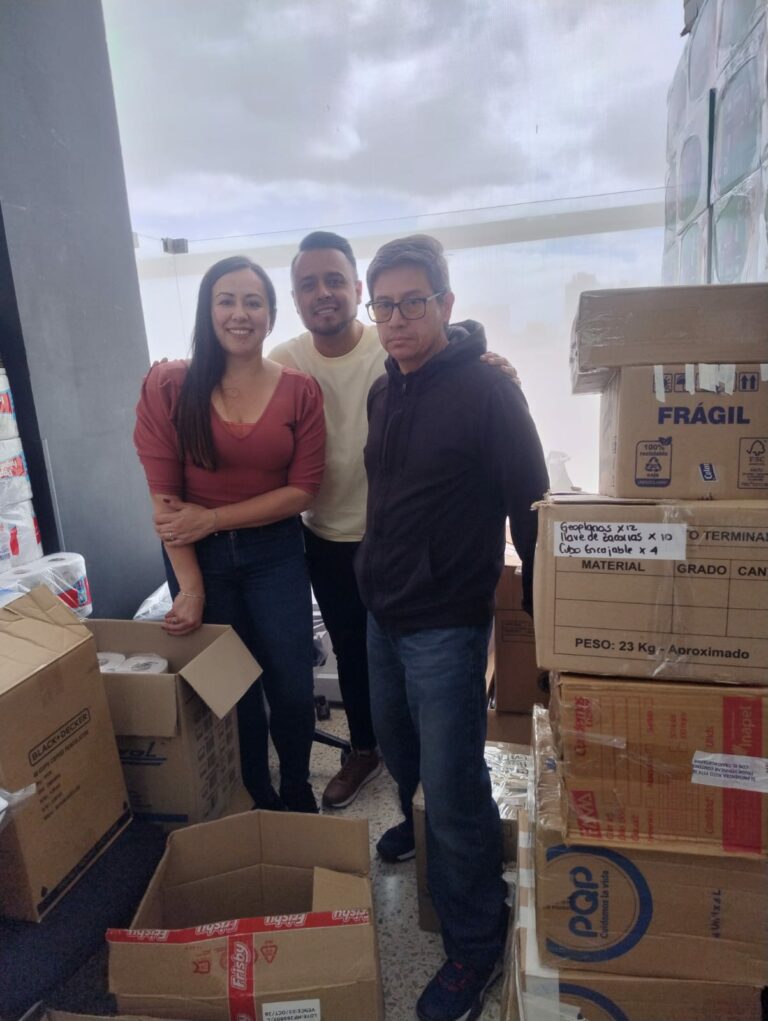 Tres integrantes del equipo del colegio entre las cajas de donaciones, antes de llevarlas al punto de acopio